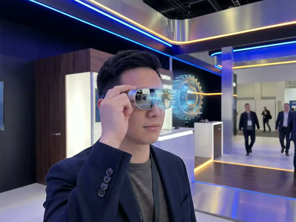 Messebesucher hält AR-Headset ans Auge, holografisches Produktdisplay über minimalistischem Ausstellungsstand mit blauem und goldenem LED-Licht.